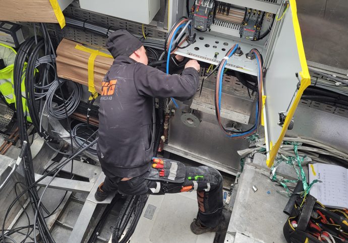 Bilden visar en man som jobbar med en elinstallation. Mannen jobbar på CKG i Uddevalla AB.